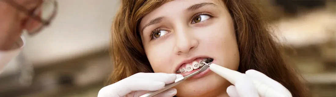 Teenage girl having braces adjusted by a dentist